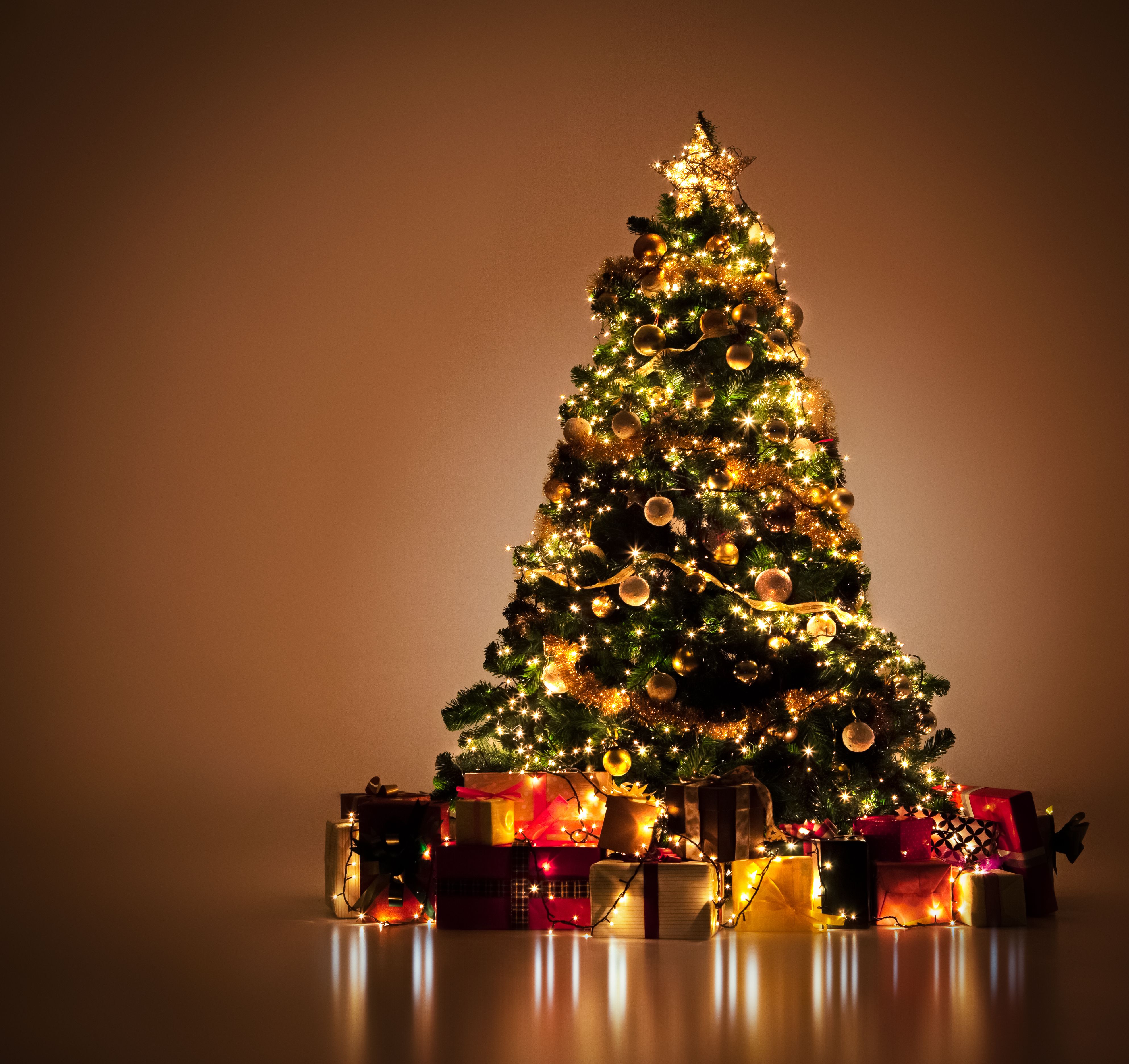Kerstboom met gouden en rode ingepakte cadeautjes eronder