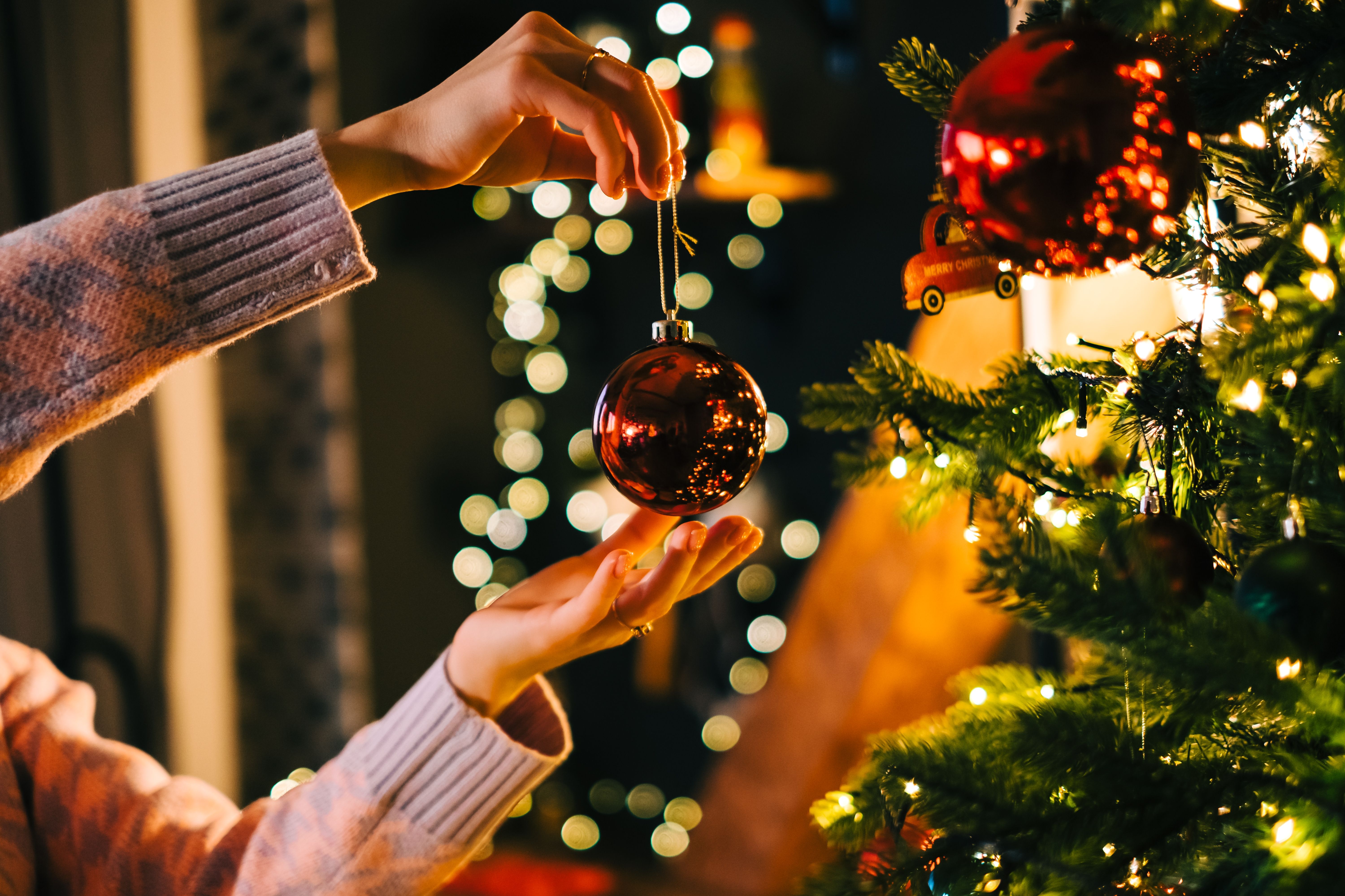 Rode kerstbal wordt opgehangen in de kerstboom